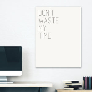 White minimalist canvas wrap wall art hanging on white bedroom wall with funny saying "don't waste my time"